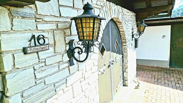 A stone wall with a street sign and two wall-mounted lanterns. - Exclusive Villa Tirol (Fieberbrunn)