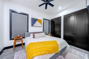 Een moderne slaapkamer met een groot bed, een plafondventilator en een kledingkast.
