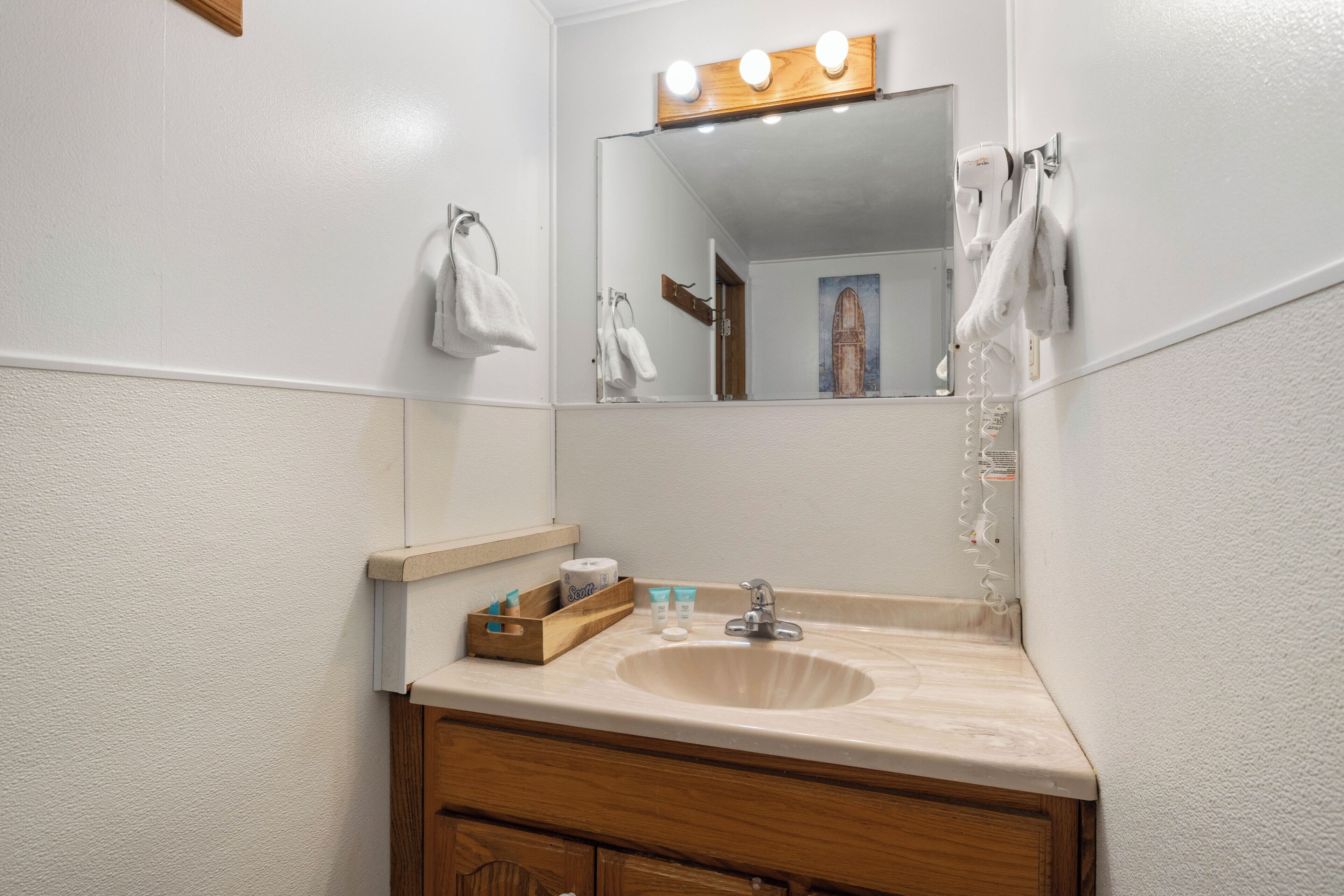 Ein Badezimmer mit Waschbecken, Spiegel, Handtuchhalter und einem Holzboden mit Toilettenartikeln.