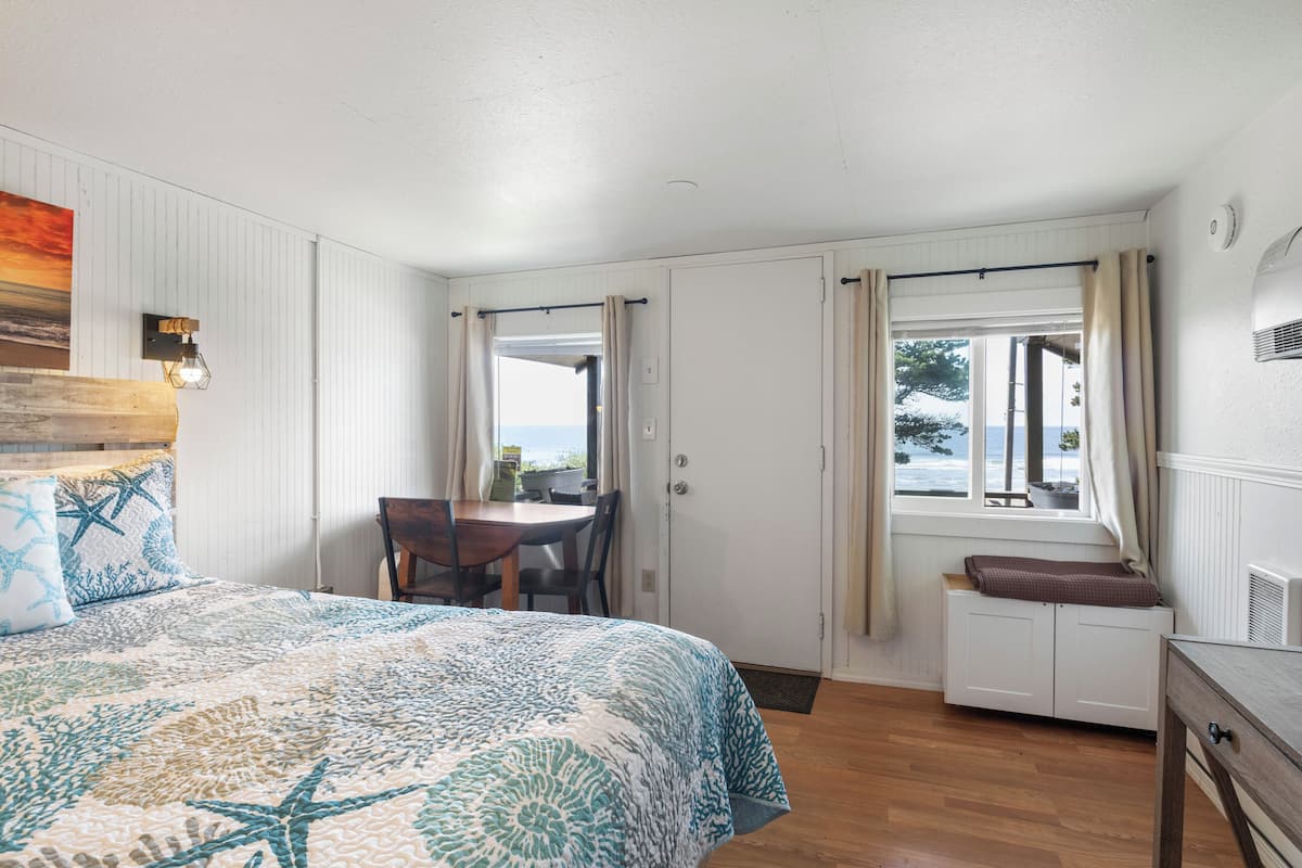A bedroom with a bed, a window with curtains, a radiator, and a view of the outdoors.