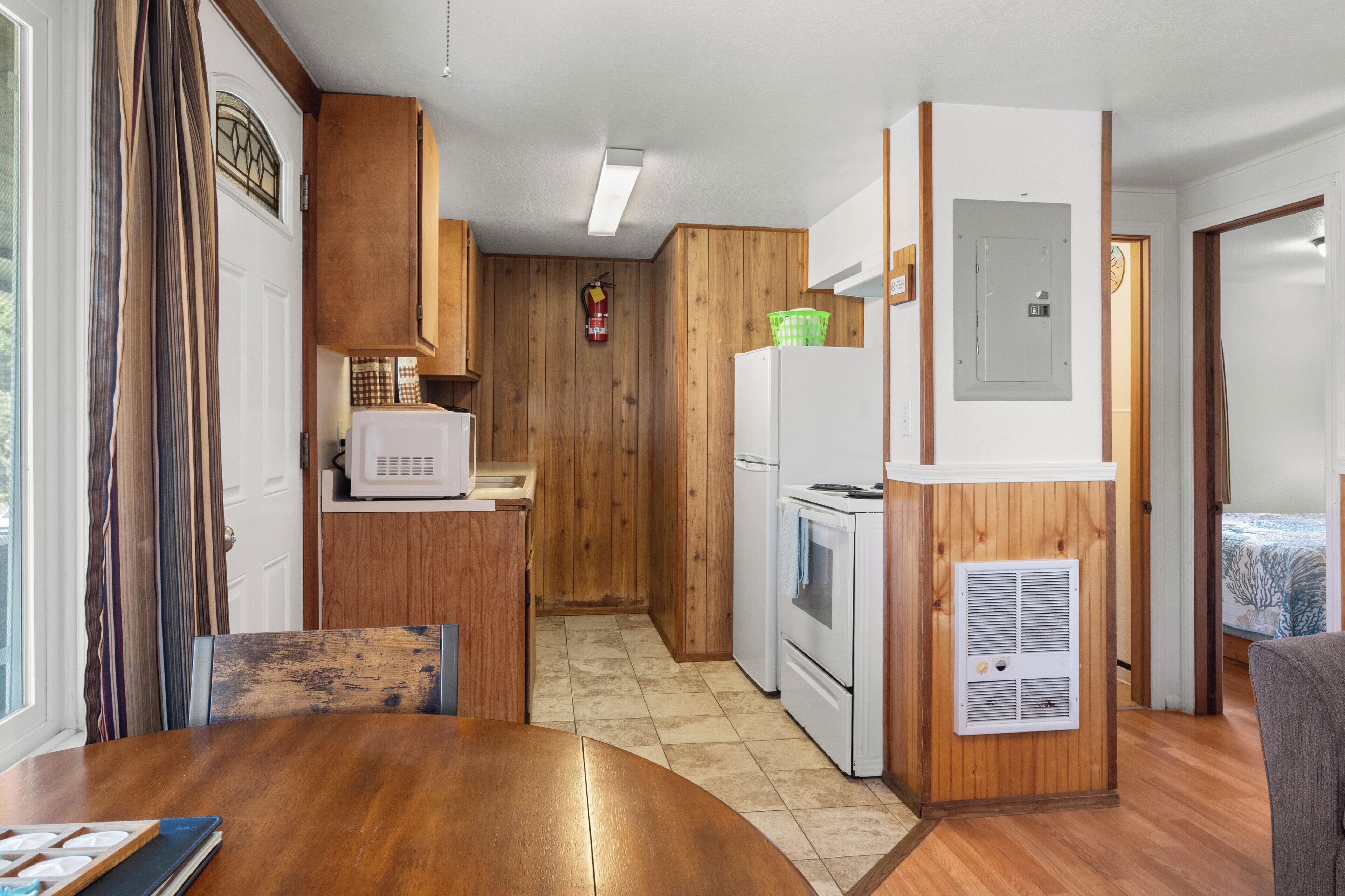 A compact kitchen with wooden cabinets, a microwave, a refrigerator, and a stove.