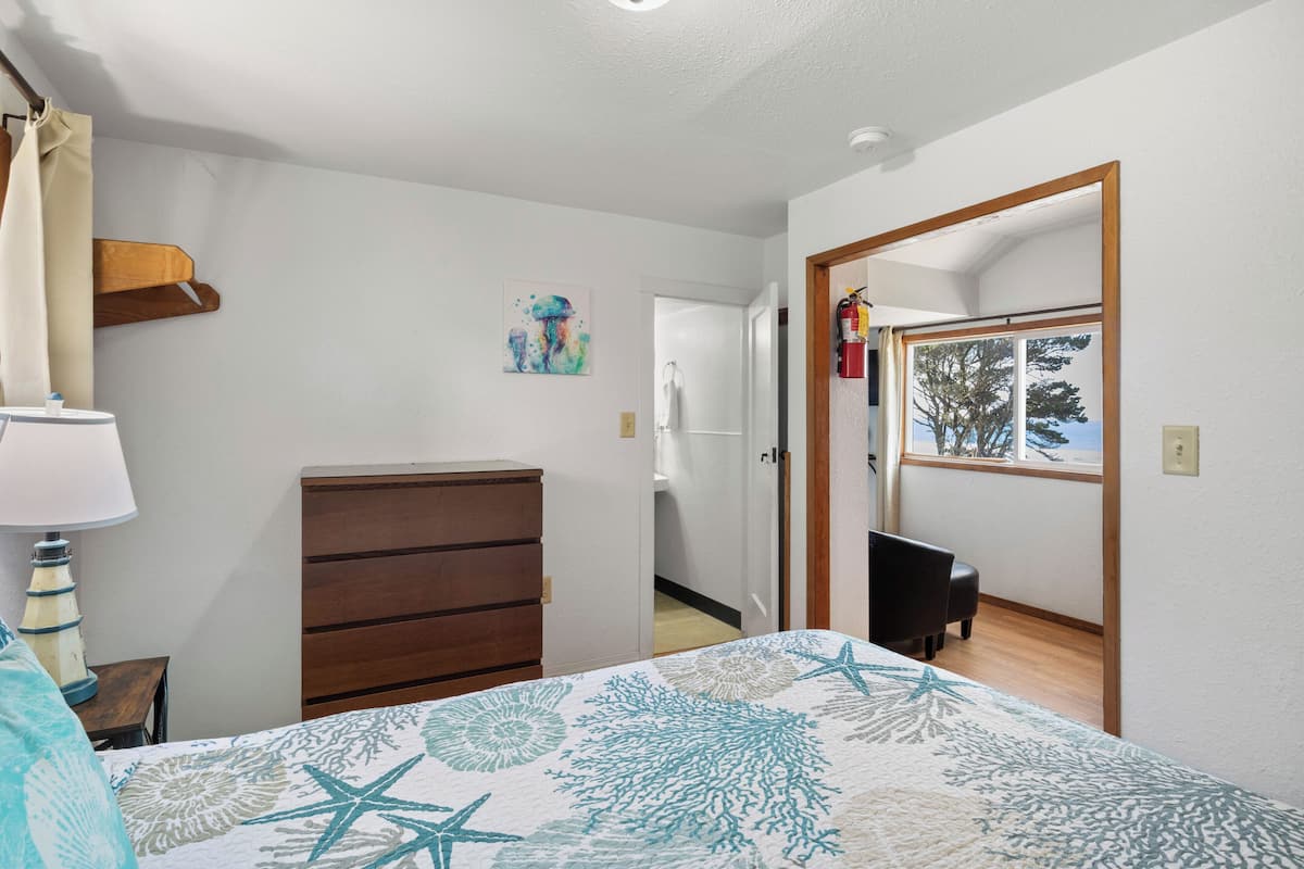 A bedroom with a bed, dresser, lamp, and a painting on the wall.