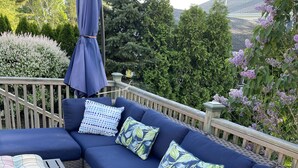 Une terrasse avec un canapé bleu foncé, des coussins à motifs et une table en bois.