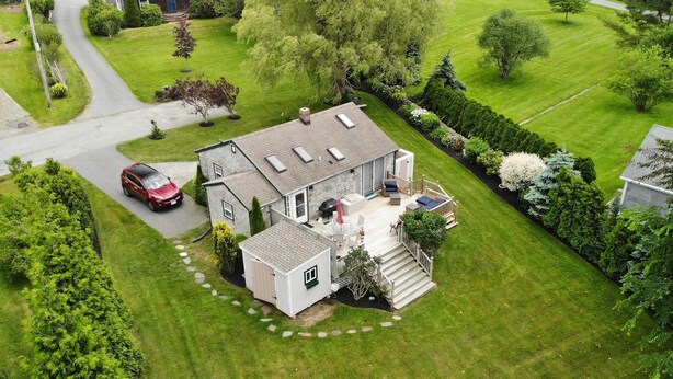 Une vue aérienne d’une maison avec une grande pelouse, une allée et un garage.