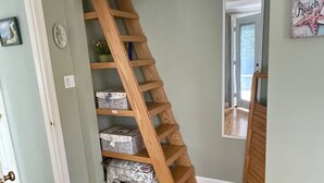 Un escalier en bois avec des boîtes de rangement à sa base, un petit tapis et une porte donnant sur une autre pièce.