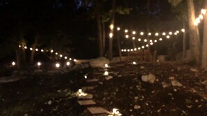 Un'area esterna illuminata da luci a tendina e con lastre di pietra come percorso.