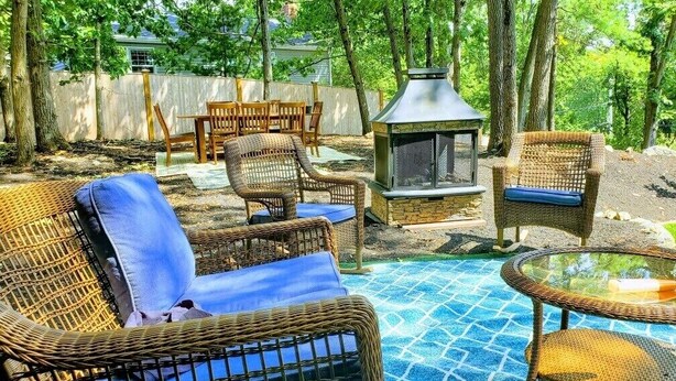Patio esterno con mobili in vimini, un braciere e una piscina con mosaici.