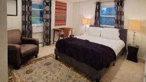 Una camera d'albergo con un letto, una sedia, una scrivania e una finestra con tende.