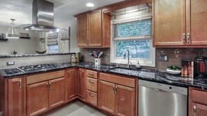 Una cucina moderna con mobili in legno, una cappa aspirante in acciaio inossidabile, una finestra con vista e una lavastoviglie.