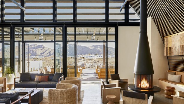Un intérieur moderne avec une grande cheminée, des sièges confortables et une vue sur les montagnes grâce à de grandes fenêtres.