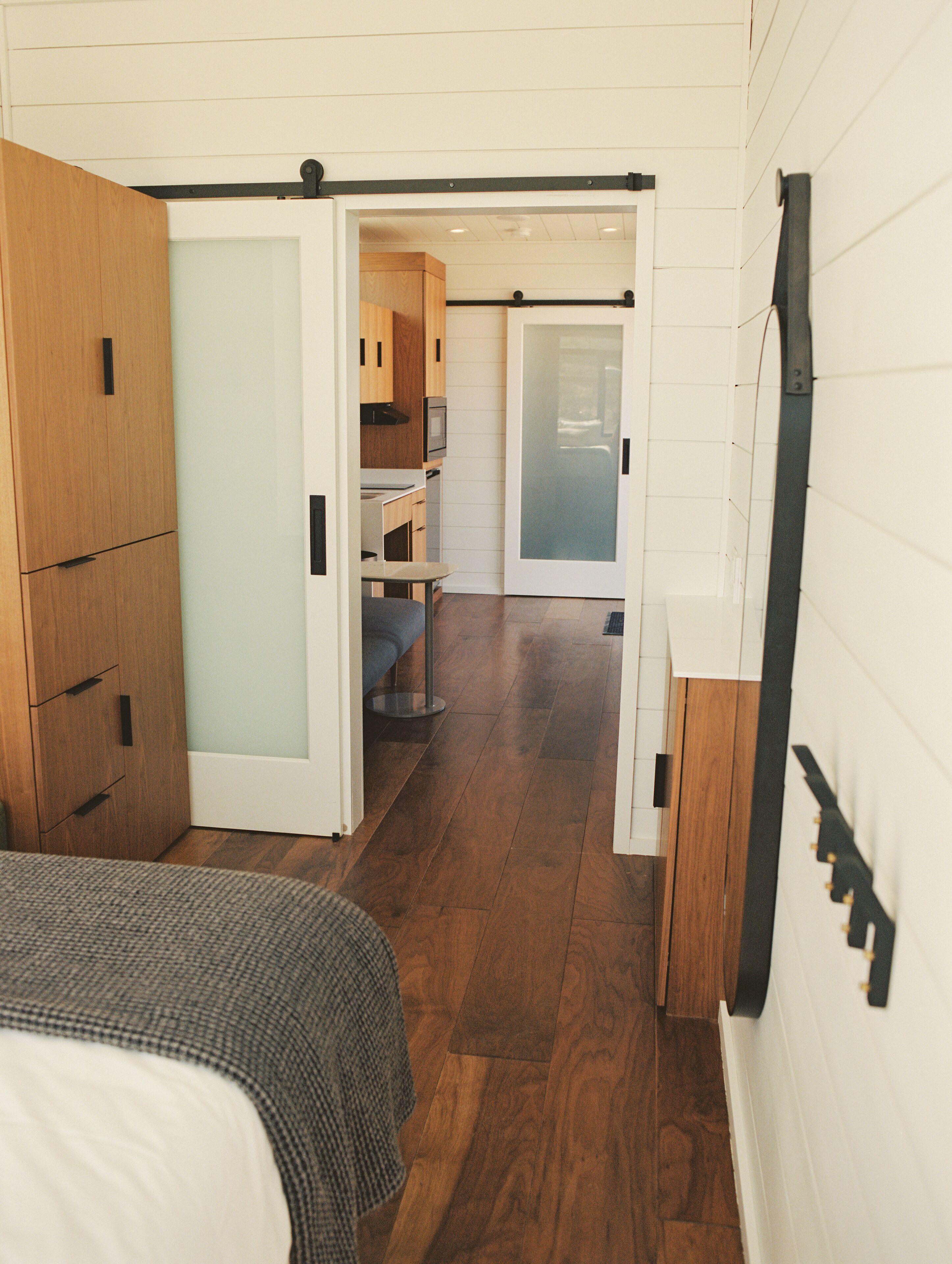 Un dormitorio con cama, armario de madera y puerta corredera que da a una kitchenette.