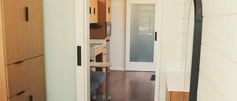 Un dormitorio con cama, armario de madera y puerta corredera que da a una kitchenette.