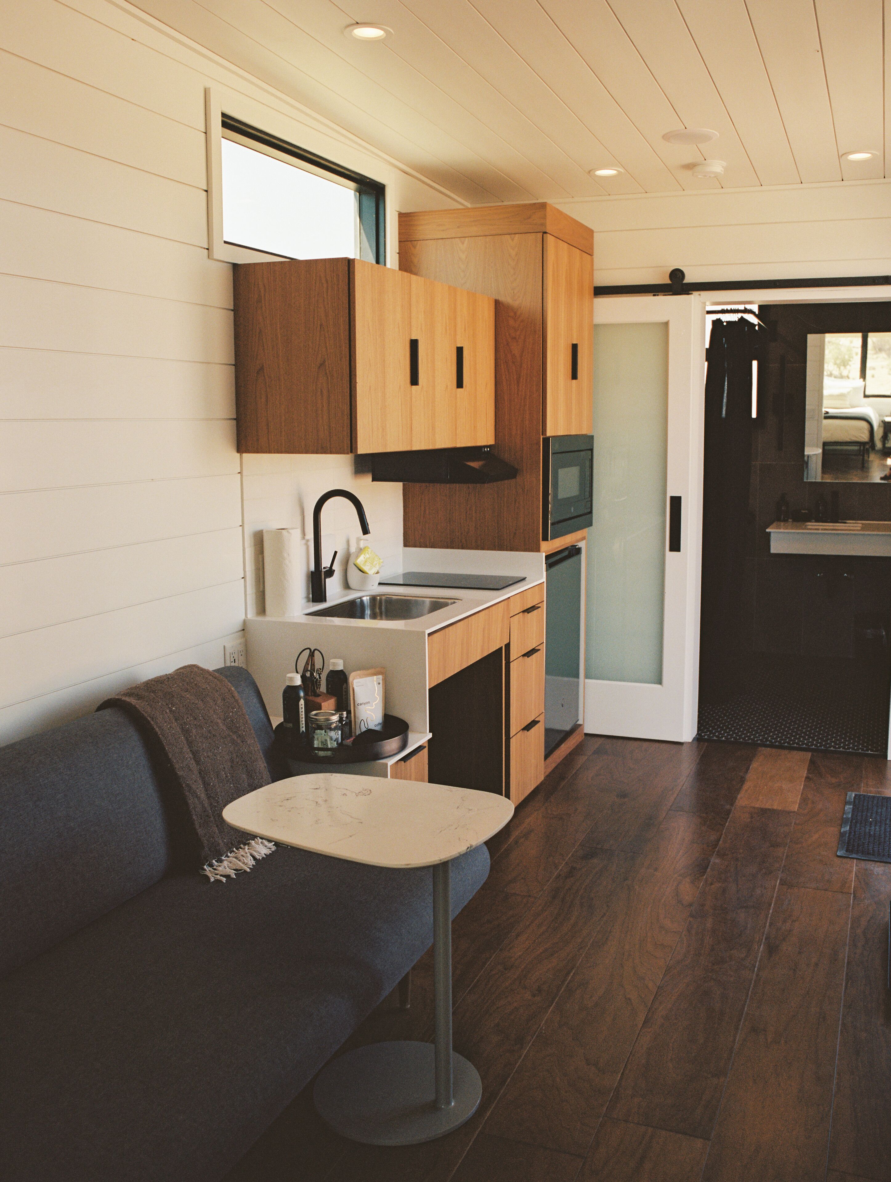 A compact kitchen with wooden cabinets, a built-in oven, and a small dining area with a round table.