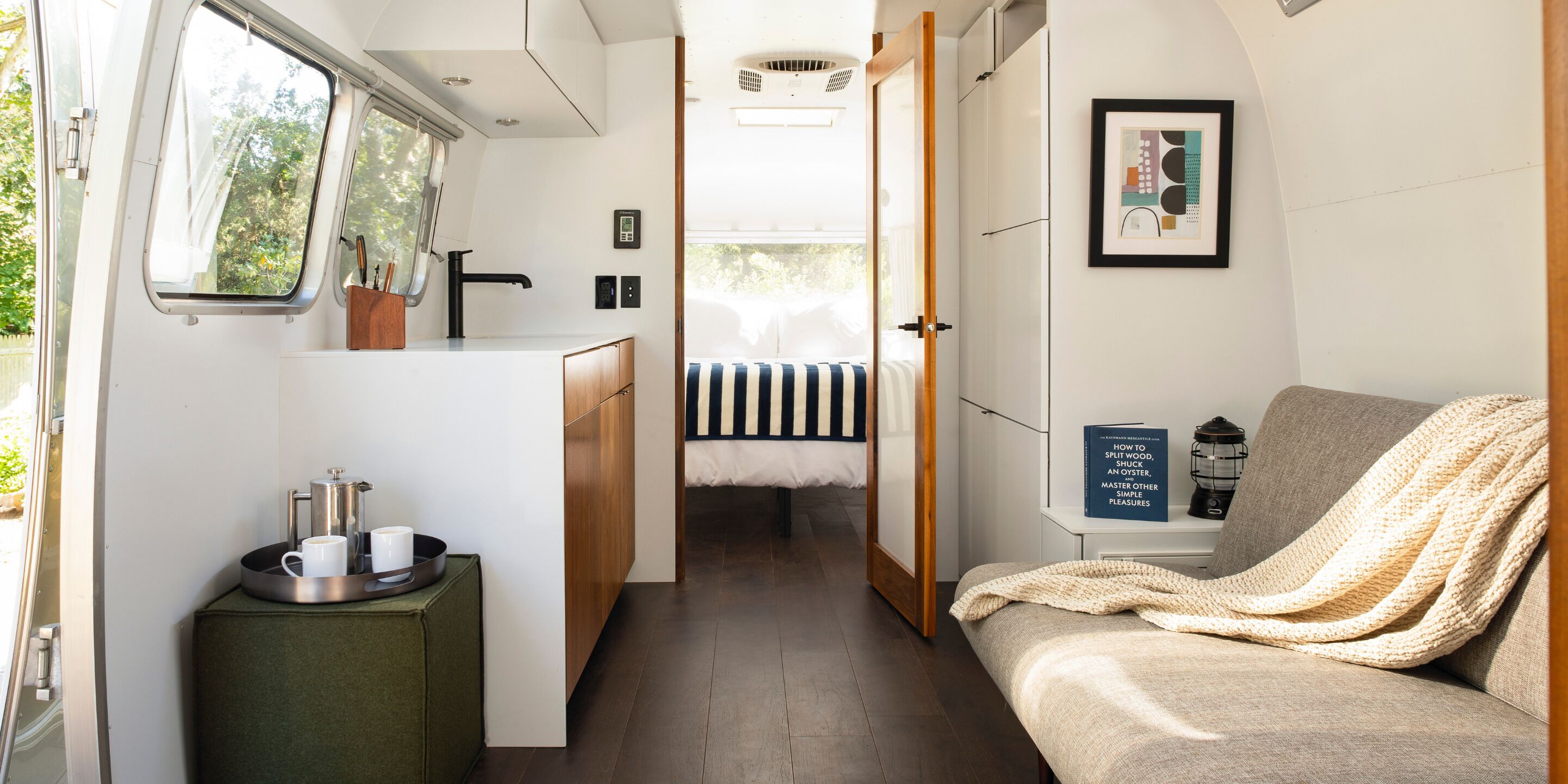 Ein kompaktes Wohnmobil-Interieur mit einer Küchenzeile, einem Bett und einer Sitzecke.