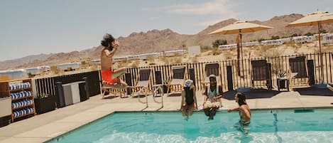 Una piscina al aire libre, sombrillas, sillones reclinables de piscina