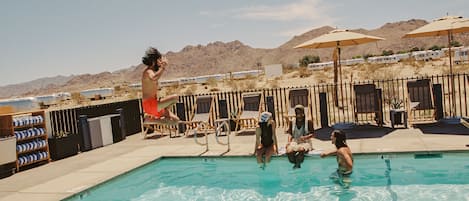 Een buitenzwembad, parasols voor strand/zwembad