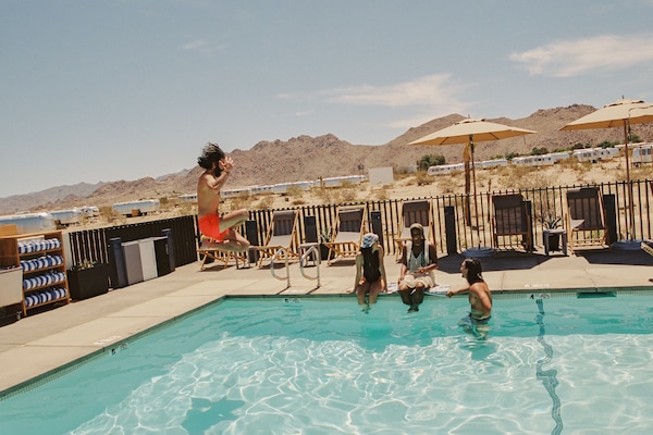 Una piscina al aire libre, sombrillas, sillones reclinables de piscina
