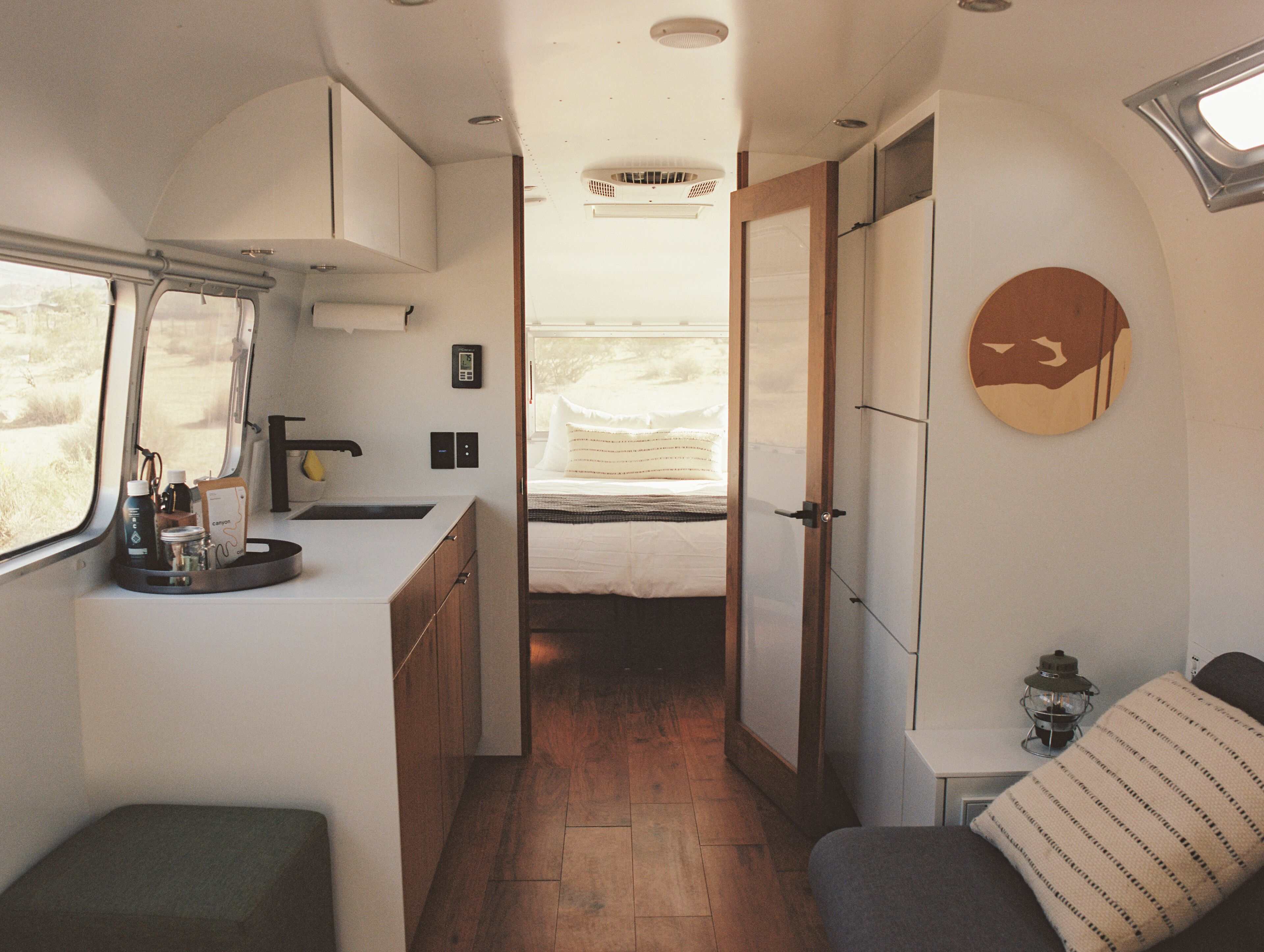 Een compact RV-interieur met een kitchenette, een zithoekje en een bed.