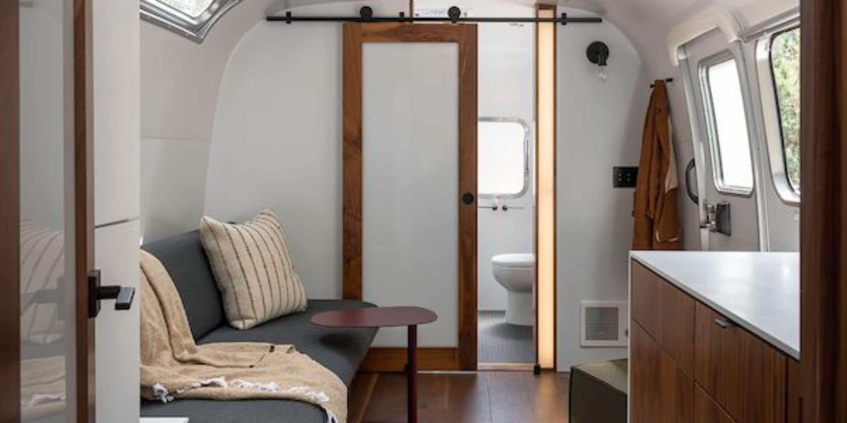 Interior compacto de autocaravana con zona de descanso, kitchenette y baño pequeño.