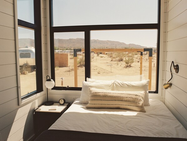 A bedroom with a large window offering a view of a desert landscape. - AutoCamp Joshua Tree (Joshua Tree)