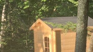 A wooden cabin with a front porch, a small window, and a door.