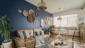 A living room with a brown leather sofa, a patterned rug, and a dining area with a white table and chairs.