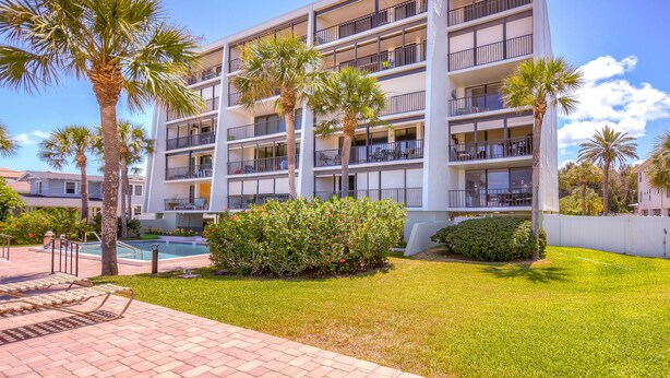 Un hôtel à plusieurs étages doté de balcons, d’une piscine et de palmiers.