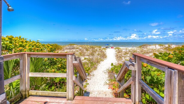 Eine Holztreppe führt zu einem Strand mit freiem Blick auf das Meer.