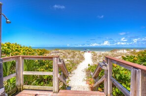 A wooden staircase leading to a beach with a clear view of the ocean. - Newly Renovated Direct Gulf Front Condo on IRB! (Indian Rocks Beach)