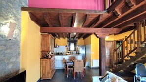 Een gezellig interieur met een eethoek, keuken en trap.