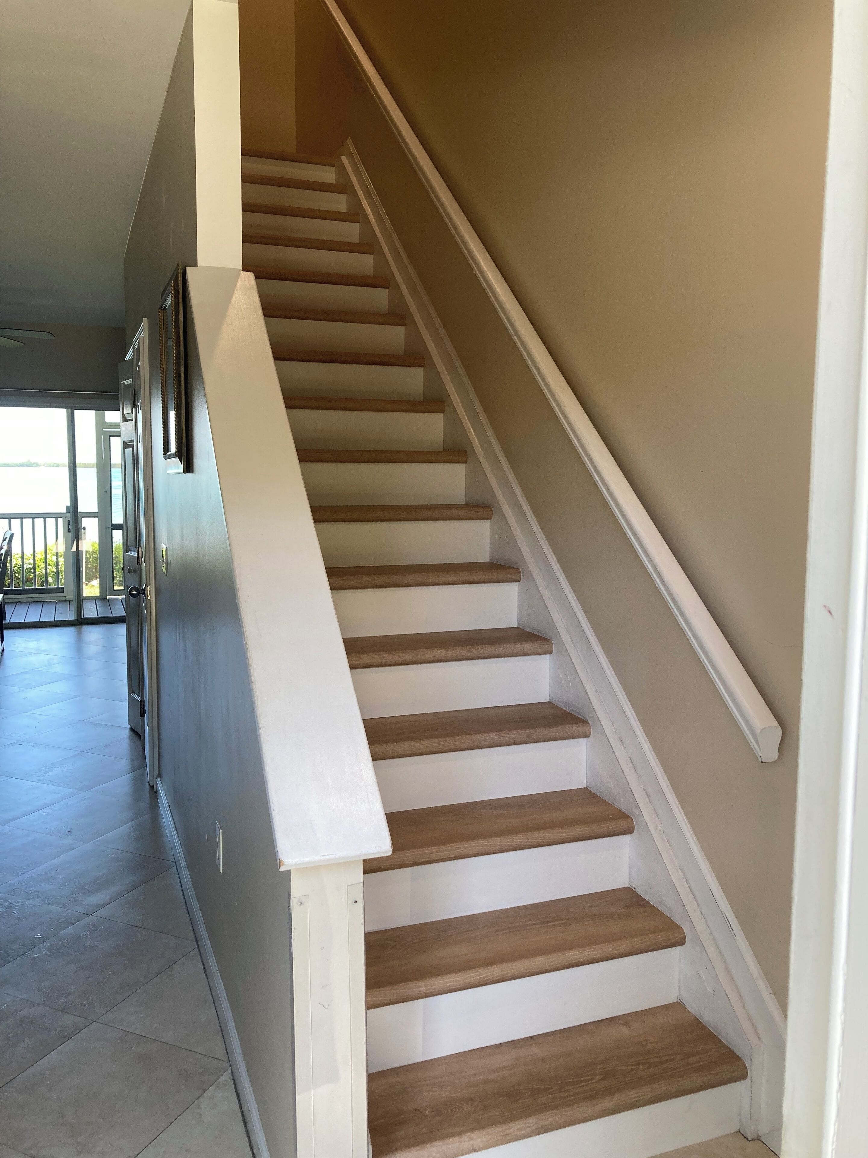 A staircase with wooden steps and white handrails, leading to an upper floor.