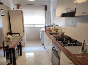 Une cuisine compacte équipée d’une cuisinière, d’un évier et d’un coin repas avec une table et des chaises.