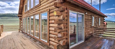 Una cabaña de troncos con terraza de madera y ventanas amplias.