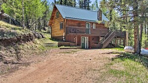 A wooden cabin with a metal roof, a front porch, and a staircase leading to a deck. - Florissant Hilltop Hideaway w/ Porch, Pond View (Florissant)