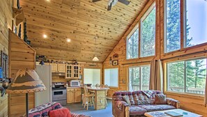 A cozy cabin interior with wooden walls, a dining area, and a sofa. - Florissant Hilltop Hideaway w/ Porch, Pond View (Florissant)