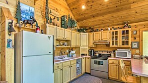 A cabin-style kitchen with wooden cabinets, a refrigerator, stove, microwave, and various decorations. - Florissant Hilltop Hideaway w/ Porch, Pond View (Florissant)