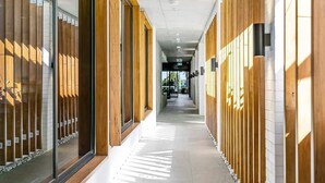 Un pasillo moderno con paneles de madera y puertas de cristal, que conduce a una zona de recepción.