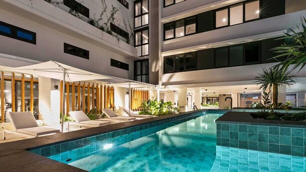 Una piscina interior moderna con sillones de descanso y una zona de estar cubierta.