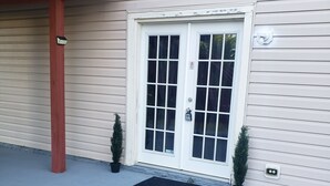 A house with a white front door, a small porch with a red railing, and a black doormat.