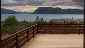Een houten terras met uitzicht op een meer en bergen.