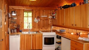 Een kleine keuken met houten kastjes, een spoelbak, een fornuis en een vaatwasser.