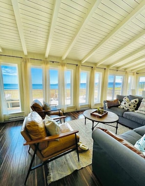 Un salón amplio con techo alto, ventanas grandes y vista al océano.