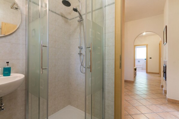 A modern bathroom with a glass-enclosed shower, a white sink, and a mirror.