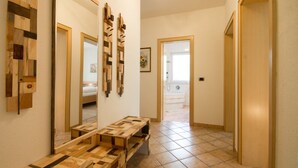 A hallway with a wooden bench, a large mirror, and a door leading to a bathroom. - Large appartment with big garden, ideal for families! (Molini di Tures)
