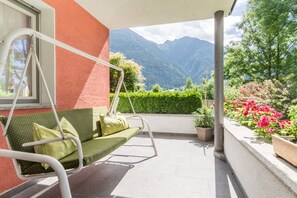 A balcony with a swing chair, potted plants, and a view of mountains.