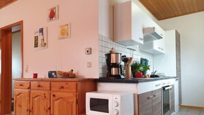 A kitchen with wooden cabinets, a microwave, a coffee maker, and a sink.