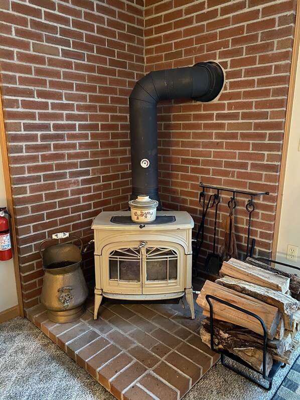 Una chimenea de ladrillo con estufa, una olla de metal y un extintor.