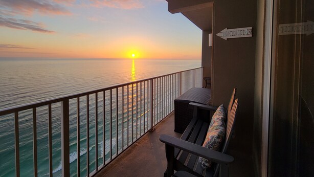 Un balcone con vista sull'oceano al tramonto, un cartello con la scritta 'BETA' e un segnale stradale.