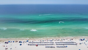 Una spiaggia con file di ombrelloni e lettini, una battigia sabbiosa e l'oceano.