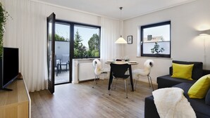Una sala de estar moderna con una mesa de comedor, sillas, un sofá y un televisor.